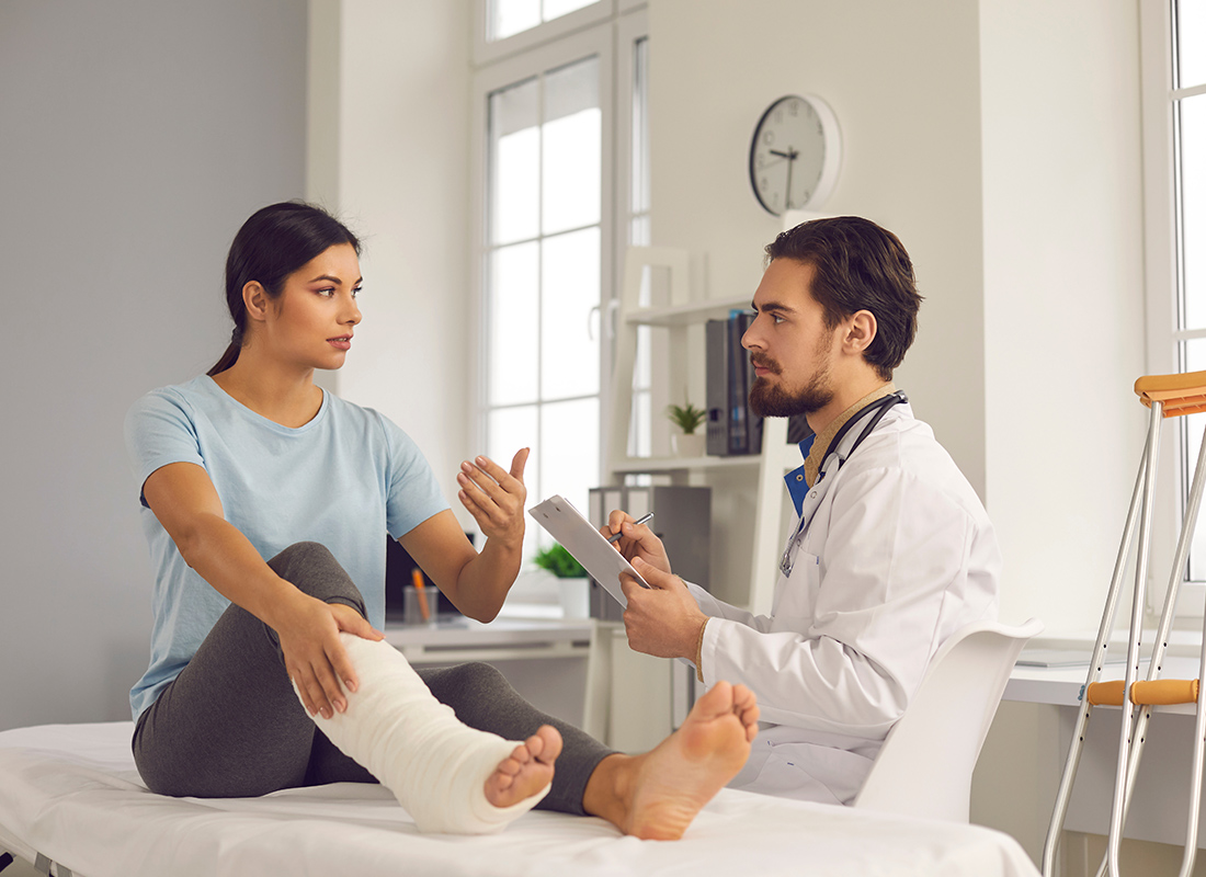 Employee Benefits - Doctor Checking Up on a Patient With a Cast on